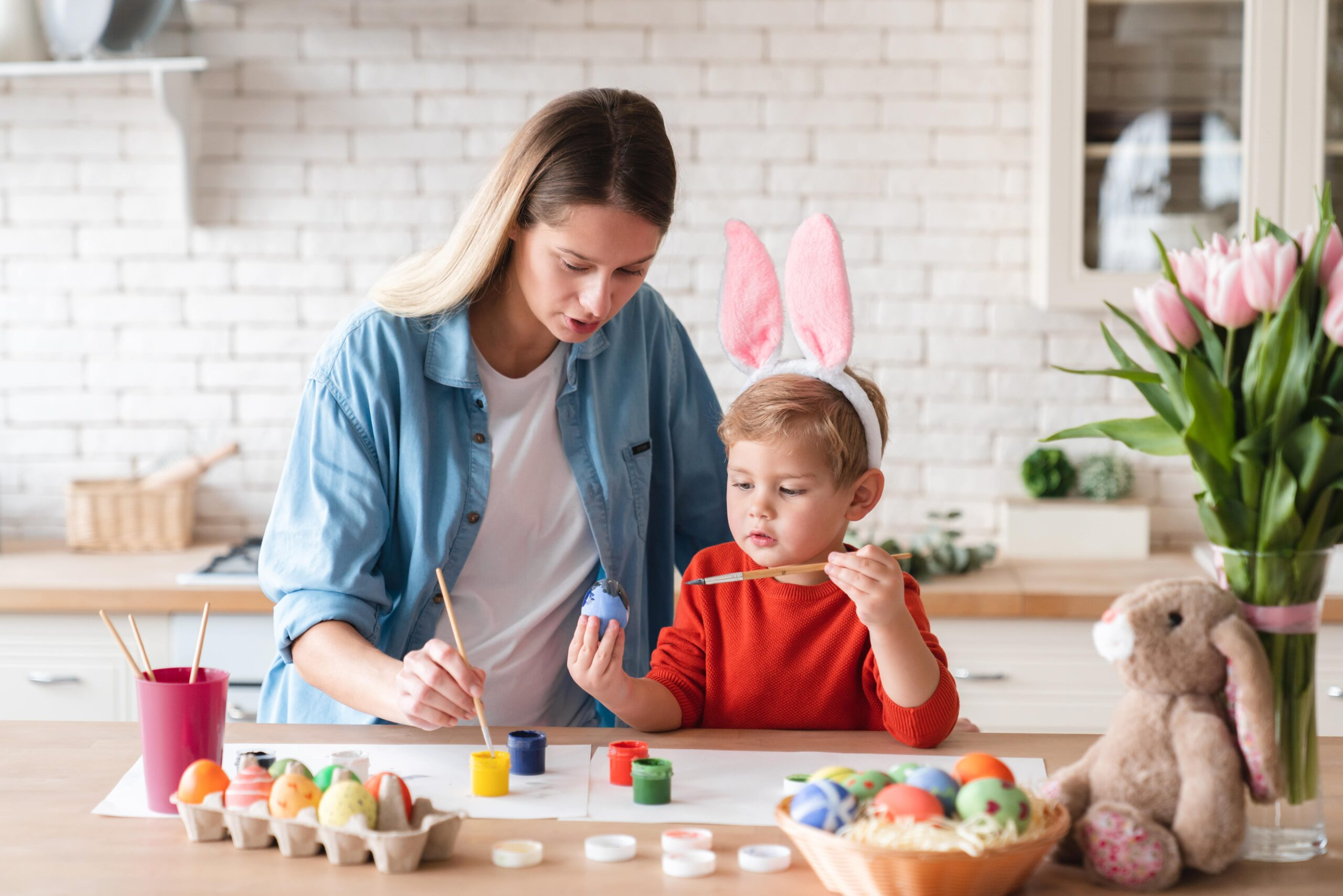 cheerful mother with her little son painting eggs easter kitchen home min scaled