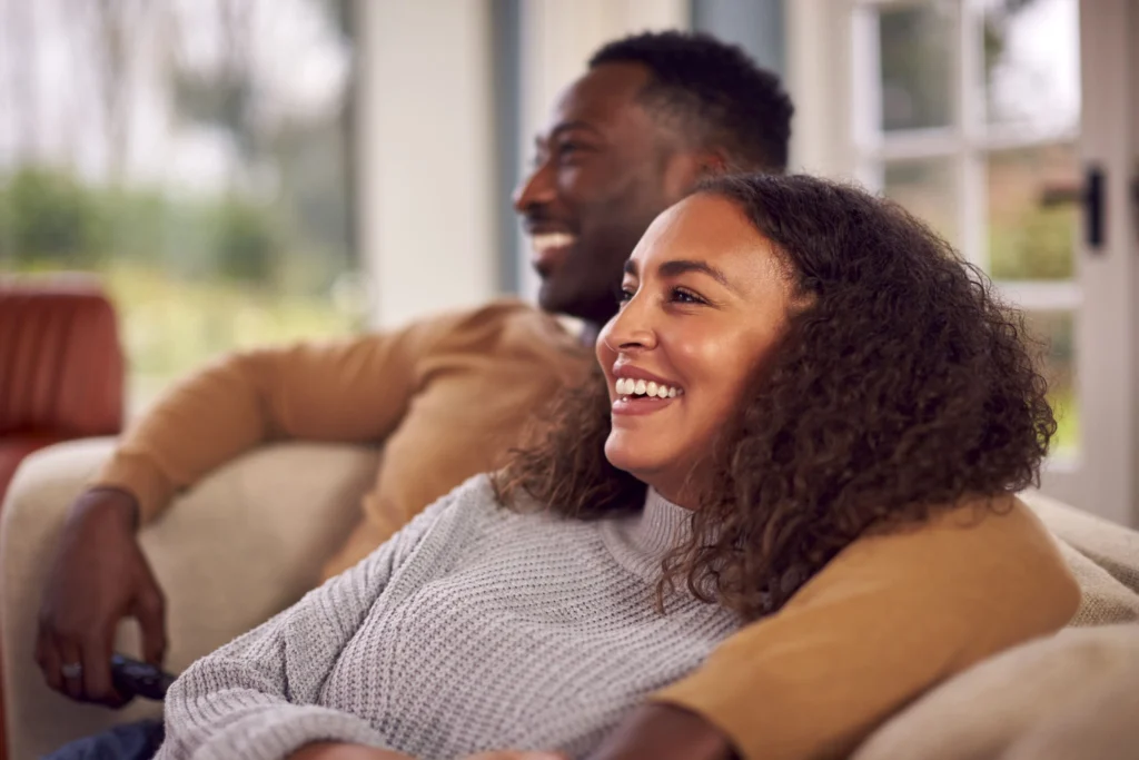 smiling couple sitting sofa home watching tv together min scaled (2)