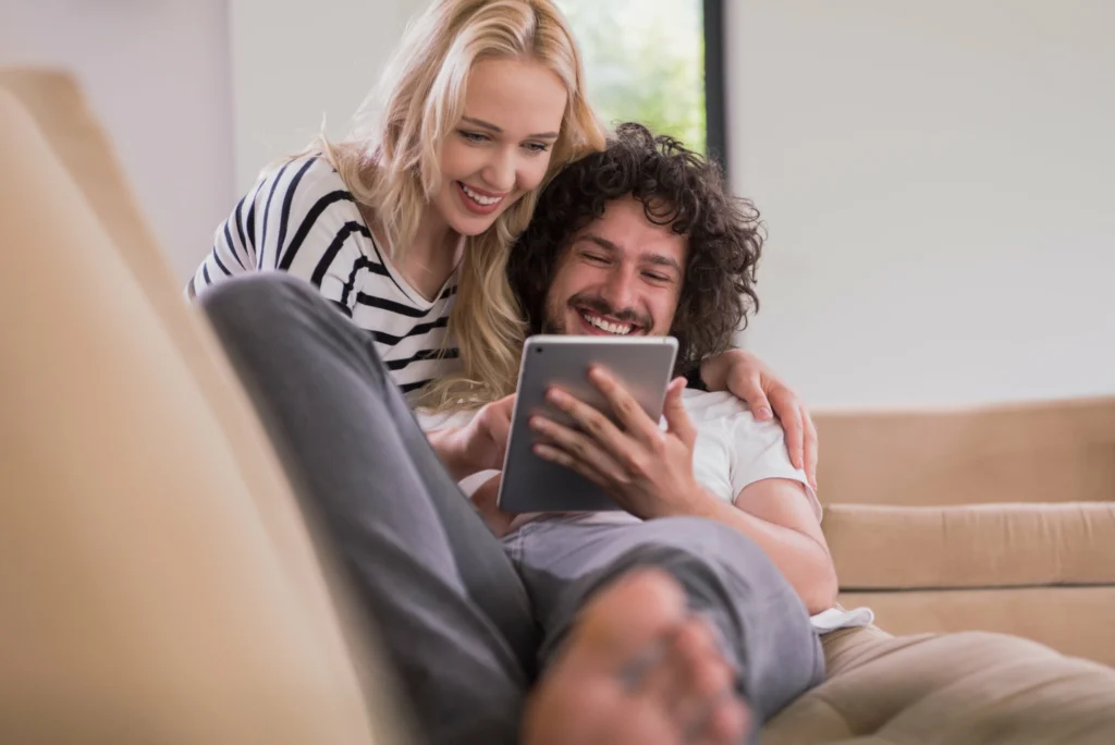 young couple relaxing luxurious home with tablet computers reading living room sofa couch min scaled