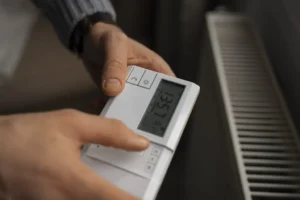 man turning off thermostat during energy crisis 1024x684