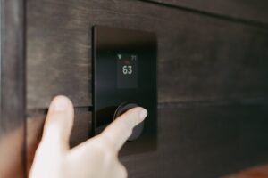 homeowner adjusting digital thermostat on interior wall
