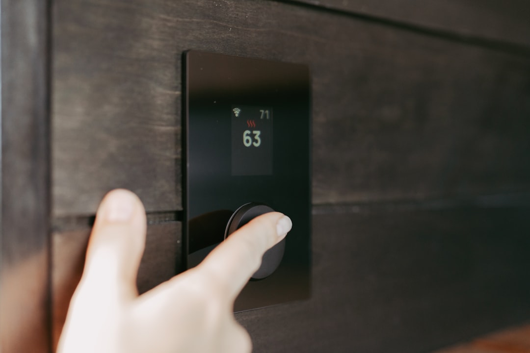 homeowner adjusting digital thermostat on interior wall